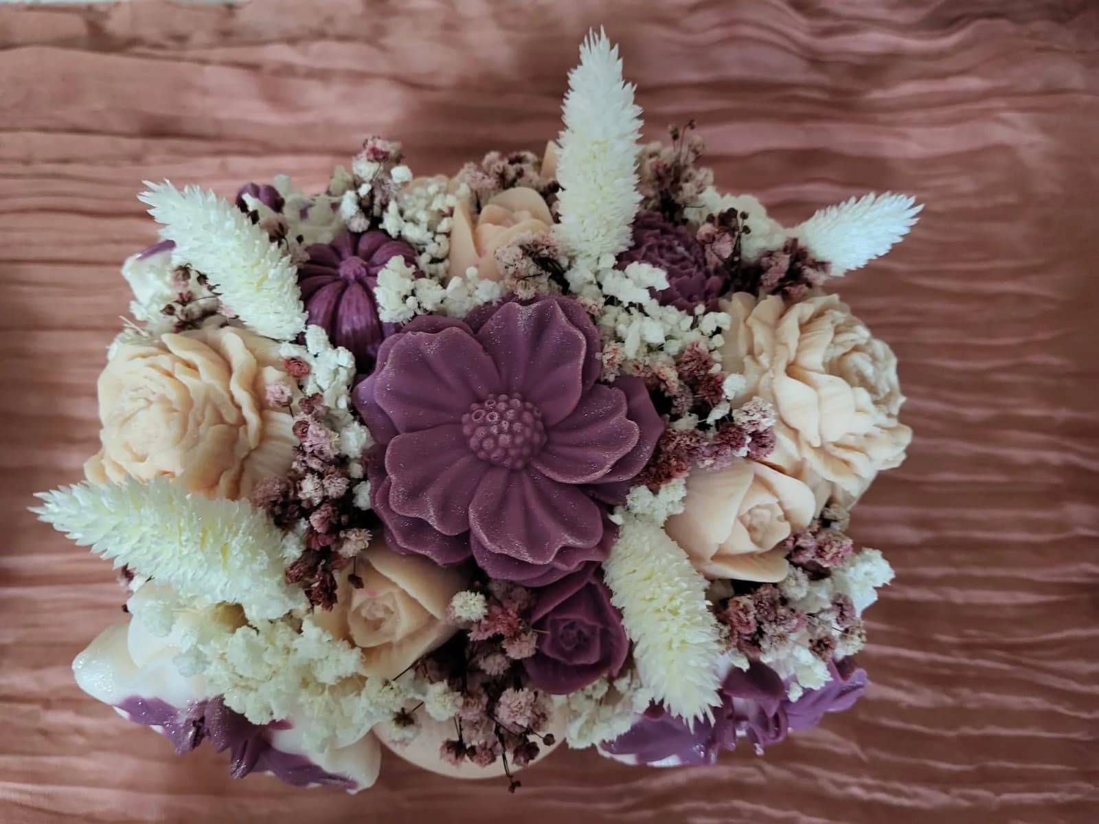 Bouquet prune et ivoire vu du dessus : une grande fleur de cire prune entourée de roses et de fleurs séchées